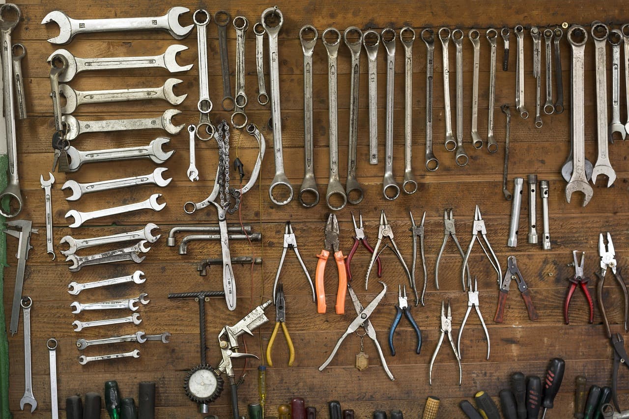 Spanners, pliers and screwdrivers hung on a wooden workshop wall